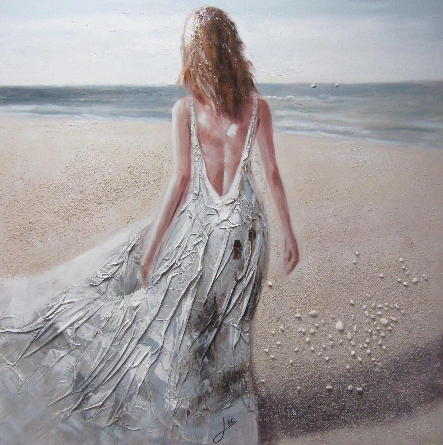 Woman in a flowing dress walking on a beach with ocean in the background