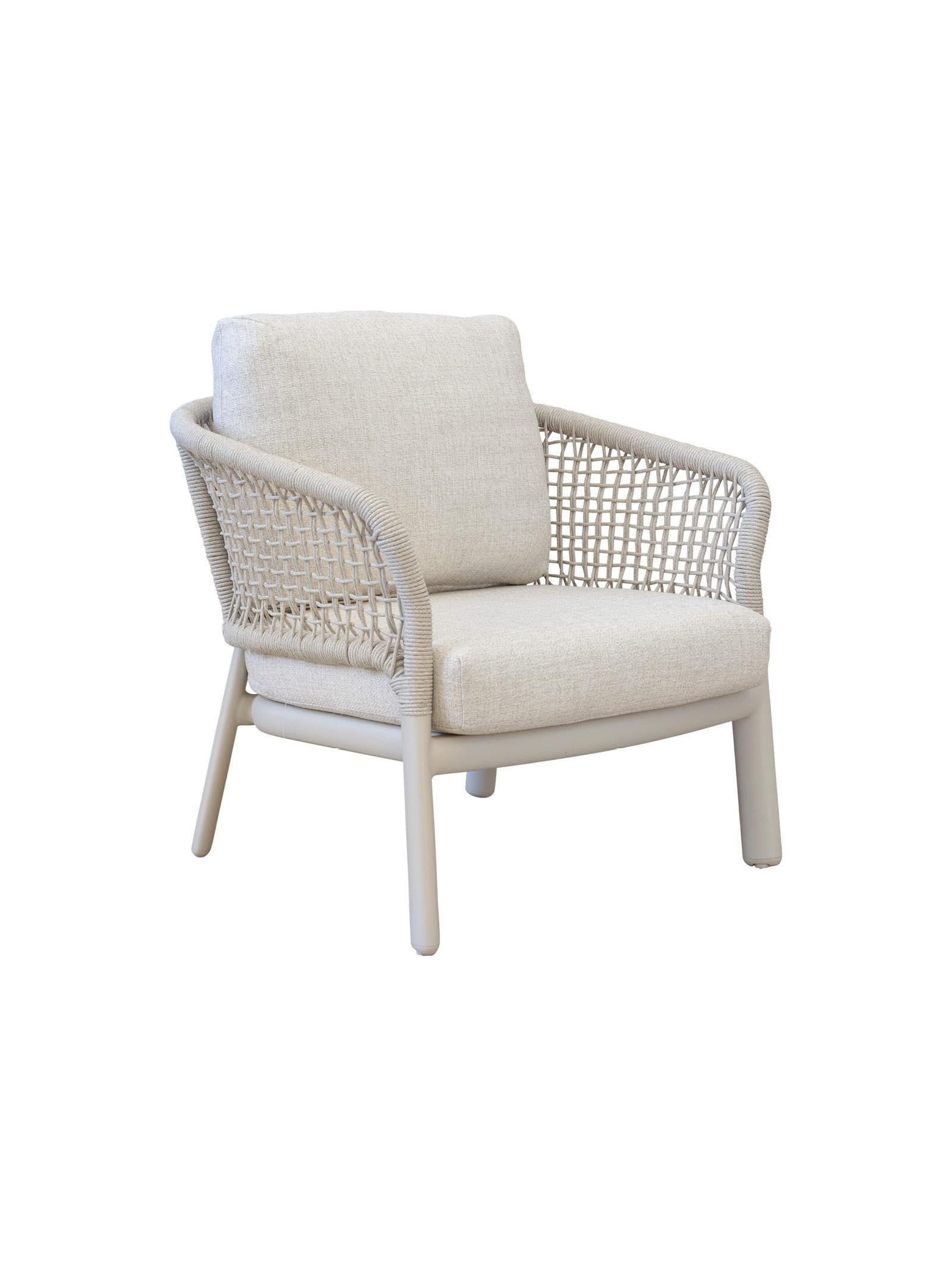 Beige armchair with woven frame and white cushions on a white background