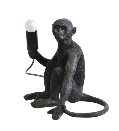 Monkey-shaped lamp holding a light bulb on a white background