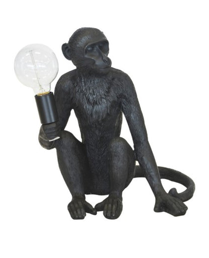 Black monkey figurine holding a light bulb on a white background