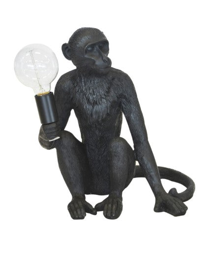 Black monkey figurine holding a light bulb on a white background