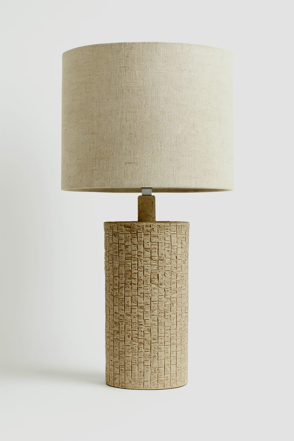Lamp with textured base and beige lampshade on a white background
