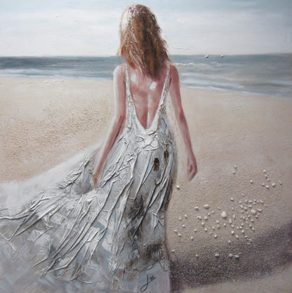 Woman in a flowing dress walking on a beach with ocean in the background