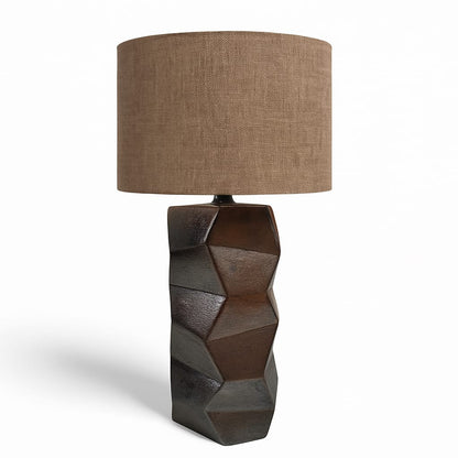 Table lamp with geometric base and brown fabric shade on a white background