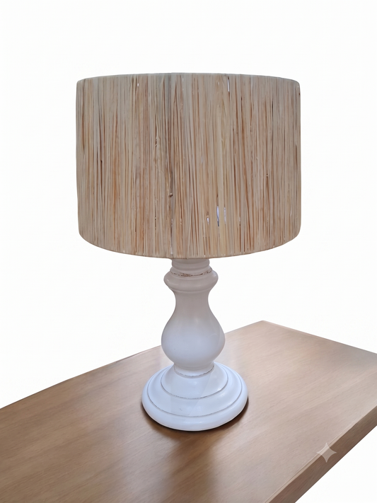 Table lamp with a beige woven shade and white base on a wooden surface.