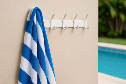 Blue and white striped towel hanging on a white wall hook with a pool in the background